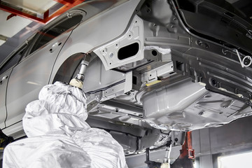The robots in the car manufacturing plant are helping the car body to be glued at the seams.