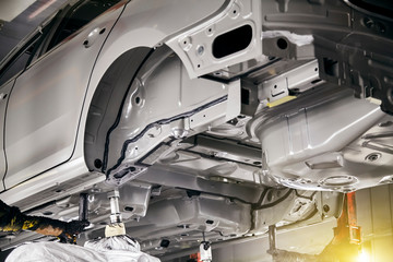 The robots in the car manufacturing plant are helping the car body to be glued at the seams.