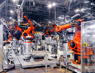 The automated robotic arm in the car manufacturing plant is busy working on the assembly line.