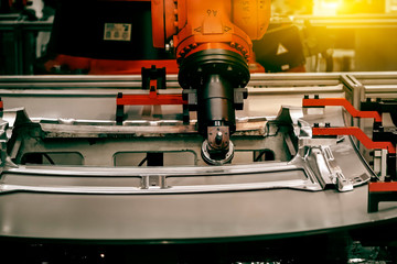 A robotic arm that is grinding the outer shell of a car in a manufacturing plant