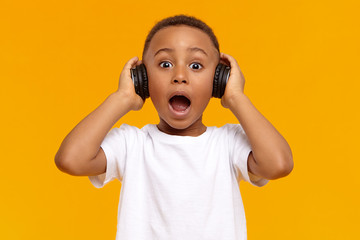 Genuine human facial expressions, emotions and modern gadgets. Emotional funny African child in...