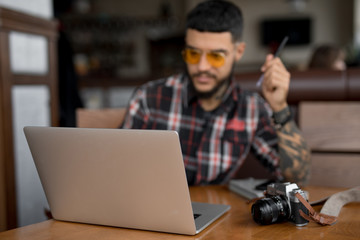 Fototapeta na wymiar Stylish handsome man freelancer looking at laptop computer in cafe