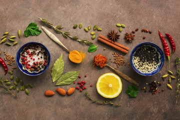 Various spices, herbs and seasonings on a brown rustic background. Top view, flat lay.