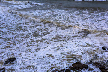 Sea waves breaking on a rocks. Deep blue sea waves hit cliff, hit rocks cliff. Mighty sea waves breaking on a cliff, splashing over rocks. Strong ocean waves hitting rocks.