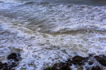 Sea waves breaking on a rocks. Deep blue sea waves hit cliff, hit rocks cliff. Mighty sea waves breaking on a cliff, splashing over rocks. Strong ocean waves hitting rocks.