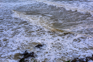 Sea waves breaking on a rocks. Deep blue sea waves hit cliff, hit rocks cliff. Mighty sea waves breaking on a cliff, splashing over rocks. Strong ocean waves hitting rocks.