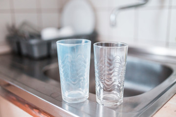 Dirty and clean glass cups on a kitchen sink. Broken washing machine concept.