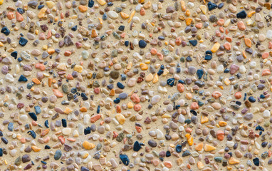Concrete wall with colorful stones and gravel as background