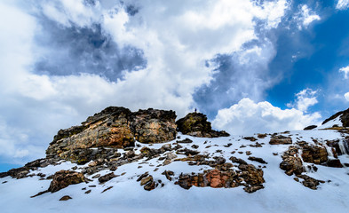 insignificant person standing on top of large mountain of rocks