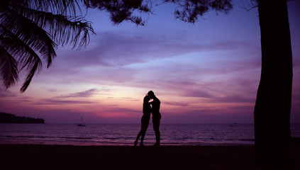 Young couple kissing on a romantic, tropical beach