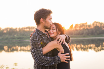 Relationship, love and nature concept - Attractive woman and handsome man hugging and kissing over water background