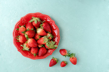 Strawberries in red plate on blue background top view 