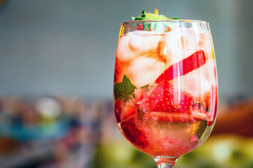 Glass with homemade srawberry mojito and berries on wood