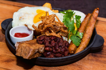 Nutricious meal with fried egg, sausages, beans, onion rings and sauce