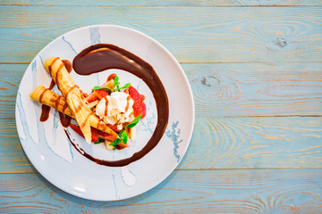 Top view delicious dessert with waffle rolls, ice cream and strawberries