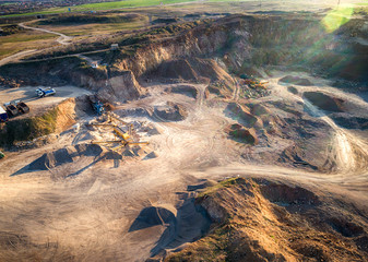 Fototapeta na wymiar Panoramic view at sunset of gravel quarry, mining of yellow construction gravel, pumping gravel with help of powerful pumps, post-apocalyptic landscape.