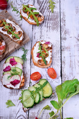 Bruschetta assortment with cream cheese, champignons, pancetta meat, vegetables and greenery