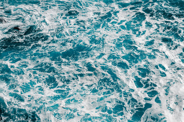 Background of blue sea water surface with white foam