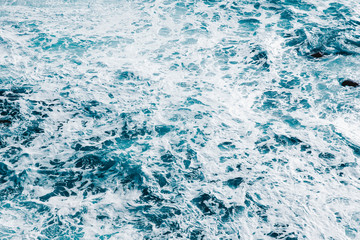 Background of blue sea water surface with white foam