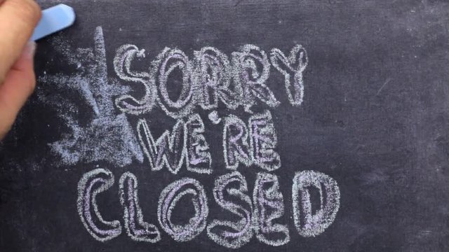 Text sorry we're closed written with chalk on old blackboard.