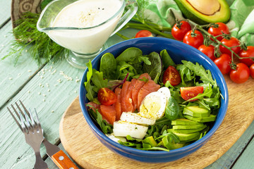 Diet menu, Vegan food. Healthy salad with arugula, Tomatoes, Salmon, Egg and Avocado on wooden table. Copy space.