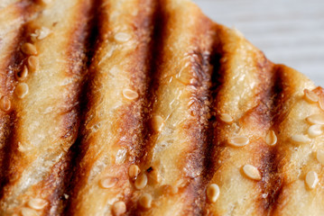 Grilled toast sprinkled with sesame seeds top view closeup. Shallow depth of field