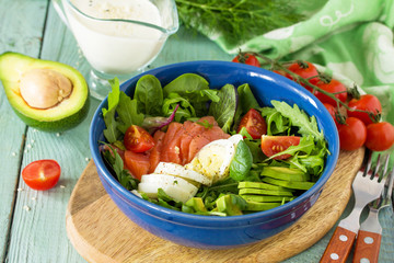 Diet menu, Vegan food. Healthy salad with arugula, Tomatoes, Salmon, Egg and Avocado on wooden table.
