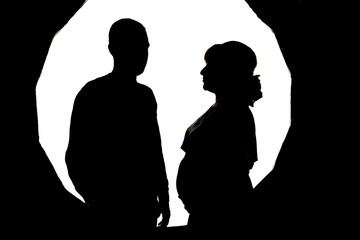 Black silhouettes of a man and a pregnant woman on a white background