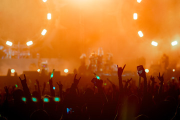 silhouettes of hand in concert.Light from the stage.