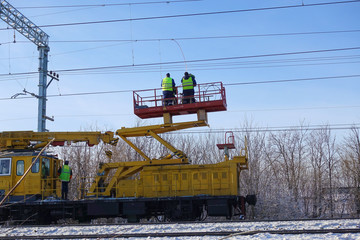 Special train with a landing crane for service and repair of electrical networks on the railway. Workers doing service work on electric lines over the rails
