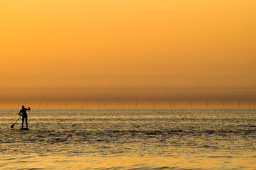 Lonely men silhouette on paddle surfing at sunset on the Zandvoort beach in the Netherlands.jpg