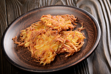Fresh homemade tasty potato pancakes in clay dish on rustic wooden table
