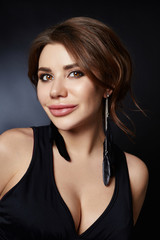 Classic portrait of a woman in a black dress on a dark background close-up. Smooth clean skin of the face girl. Large woman eyes and pouty lips