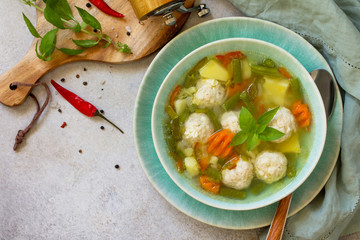 Healthy and tasty lunch. Baby food. Dietary Summer light vegetable soup with meatballs on stone table. Copy space, top view flat lay background.