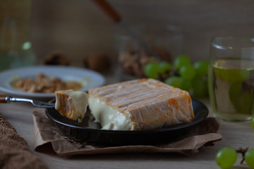 French soft cheese with mold from Alsace on a marble stone with walnut, honey, grapes and white wine