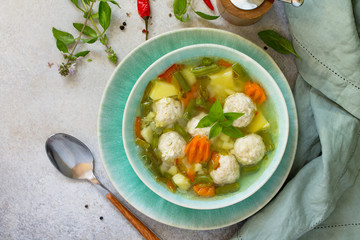 Healthy and tasty lunch. Baby food. Dietary Summer light vegetable soup with meatballs on stone table. Top view flat lay background.
