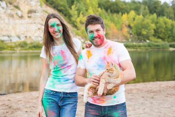 Festival holi , tourism and nature concept - Portrait of woman and man with cat covered multi-colored dust