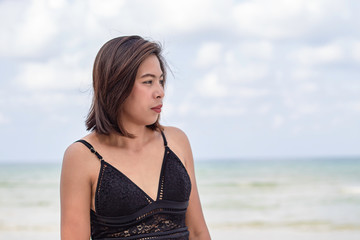 Fototapeta na wymiar Portrait of Asian woman wearing a swimsuit background sea and sky