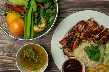 a plate of chicken rice with soup and sauce on wooden background. top view