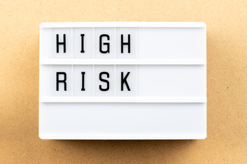 Light box with word high risk on wood background