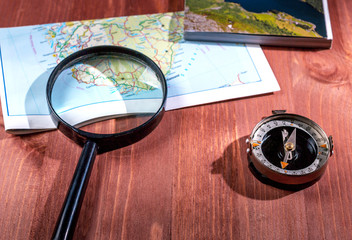 Map, compass and magnifier on wooden background