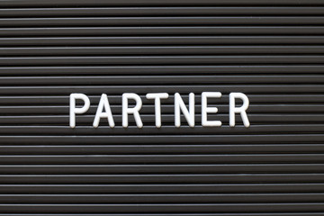 Black color felt letter board with white alphabet in word partner background