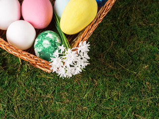 Basket with colorful Easter eggs on green grass