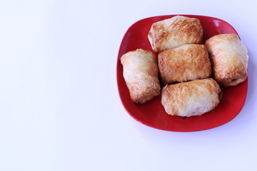 Close-up- Fried pies lie on a red plate. The background is white.