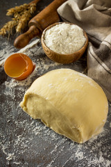 Dough, baking background. Raw dough ball for bread or pizza on a dark table. Copy space.