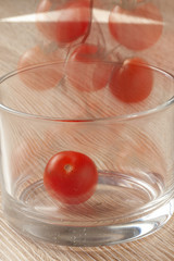 Cherry tomatoes in a glass tumbler on a wooden table