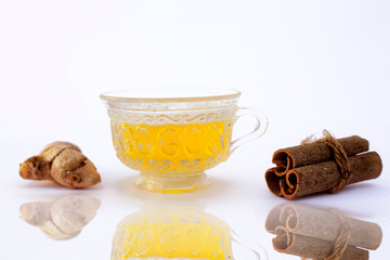 Popular turmeric tea isolated on white with its entire ingredients which are turmeric powder and raw, honey and cinnamon sticks.Used for detoxifying body.Isolated on white along with its reflection.