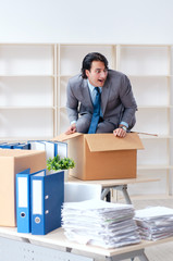 Young man employee with boxes in the office 