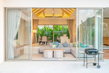 Luxury interior design in living room of pool villas. Airy and bright space with high raised ceiling, sofa, middle table, dining table and open kitchen home, house, building , resort