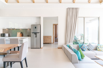 Luxury interior design in living room of pool villas. Airy and bright space with high raised ceiling with open kitchen
